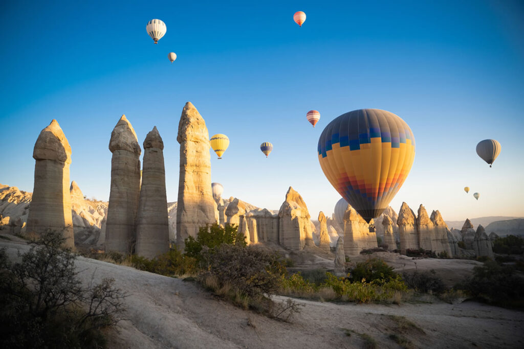 A colorful hot air balloon floating above Cappadocia’s fairy chimneys during sunrise.