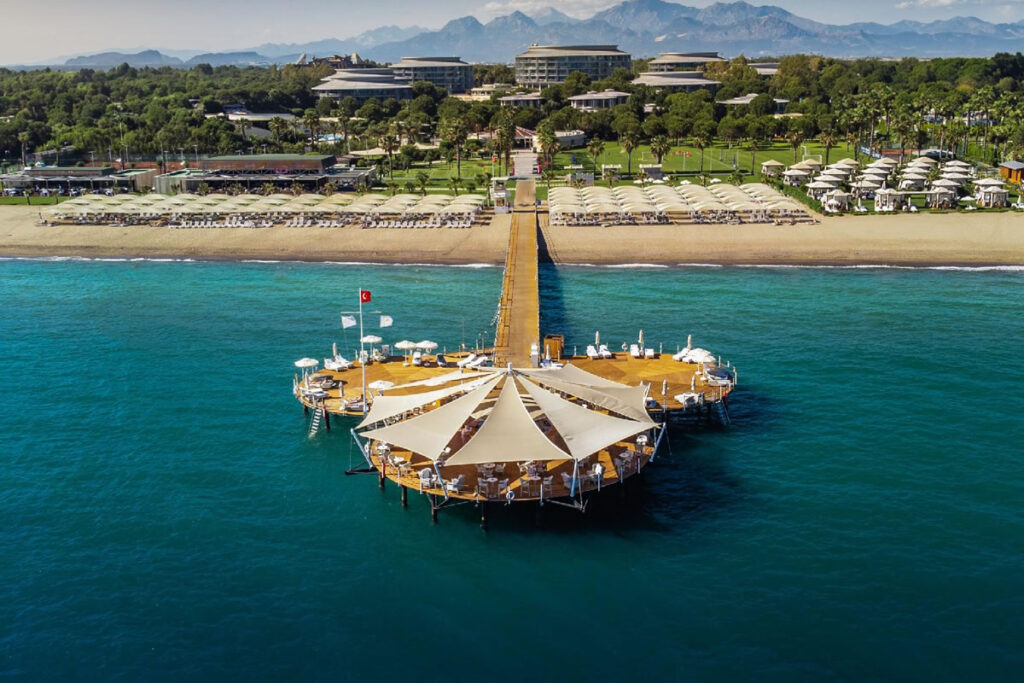 Infinity pool and sunbeds at a luxury beach resort in Antalya with sea views.
