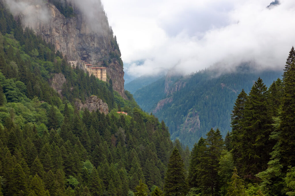 Sumela Monastery surrounded by lush greenery and dense forests in the Black Sea mountains.