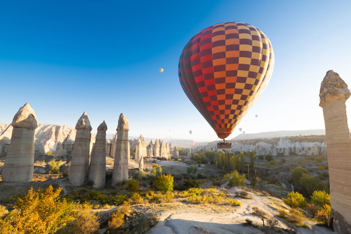 Hot air balloons rising over the fairy chimneys of Cappadocia at sunrise, Turkiye.