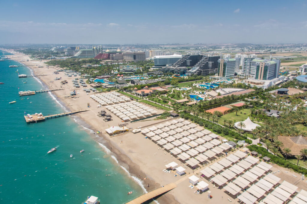 "A luxury resort along Lara Beach in Antalya with private pools and palm-lined paths.